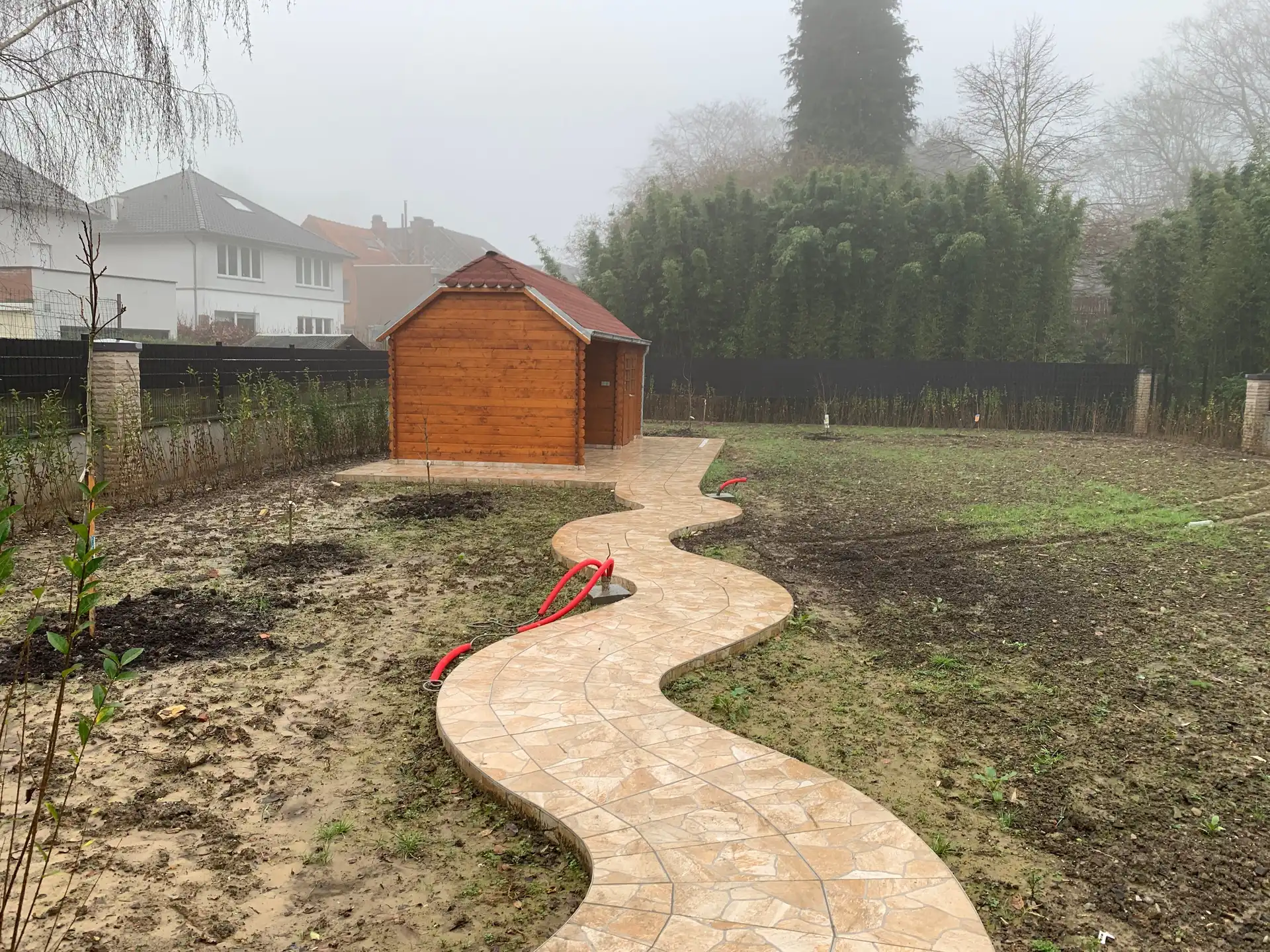 Le même jardin plus tôt dans le chantier : l’allée sinueuse en pierre naturelle est posée, la terre est encore nue avec de jeunes plantations