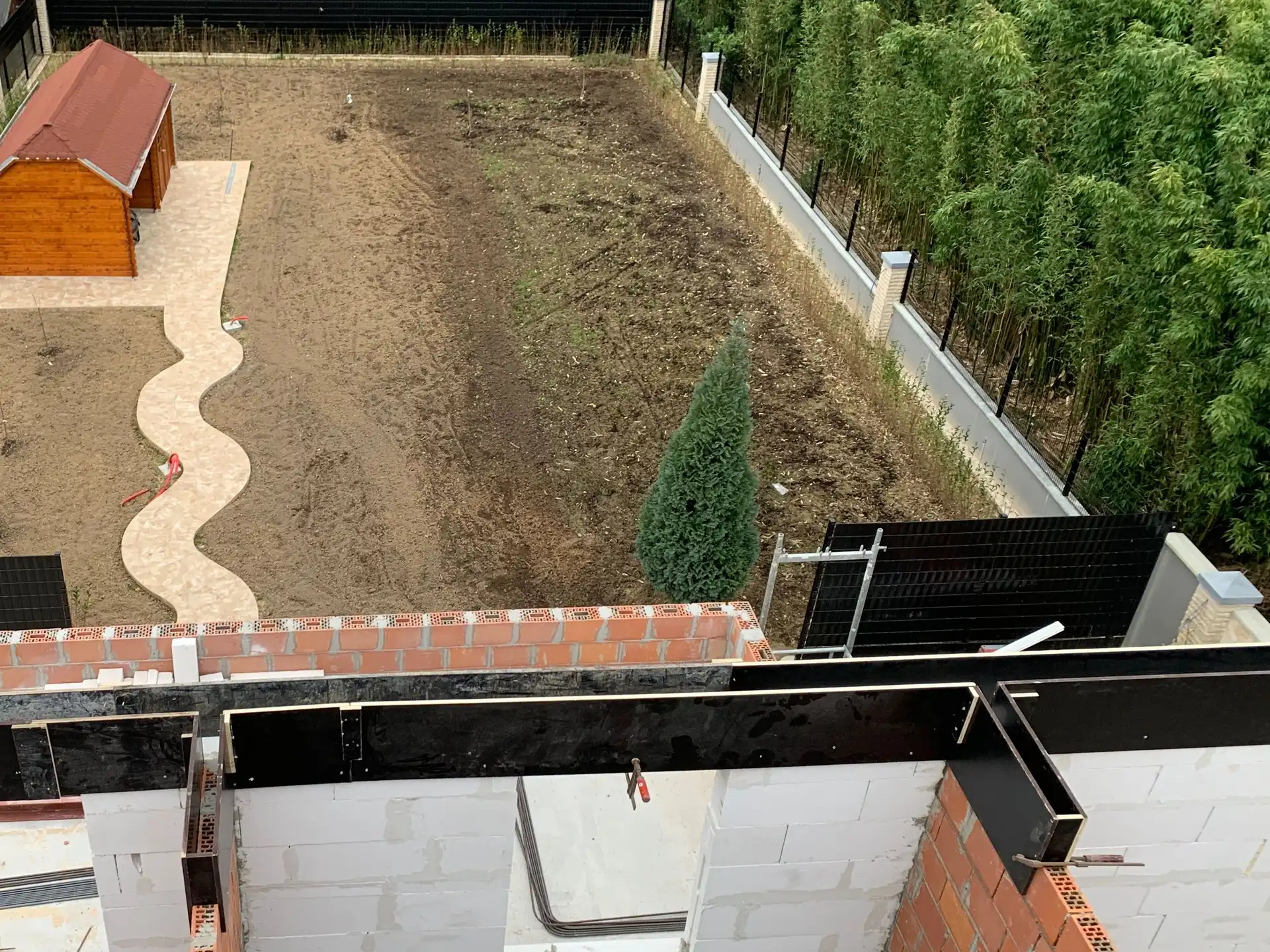 Le même point de vue pendant le chantier : les murs du nouvel étage en blocs cellulaires et briques avec armatures, et derrière, le jardin encore en terre nue