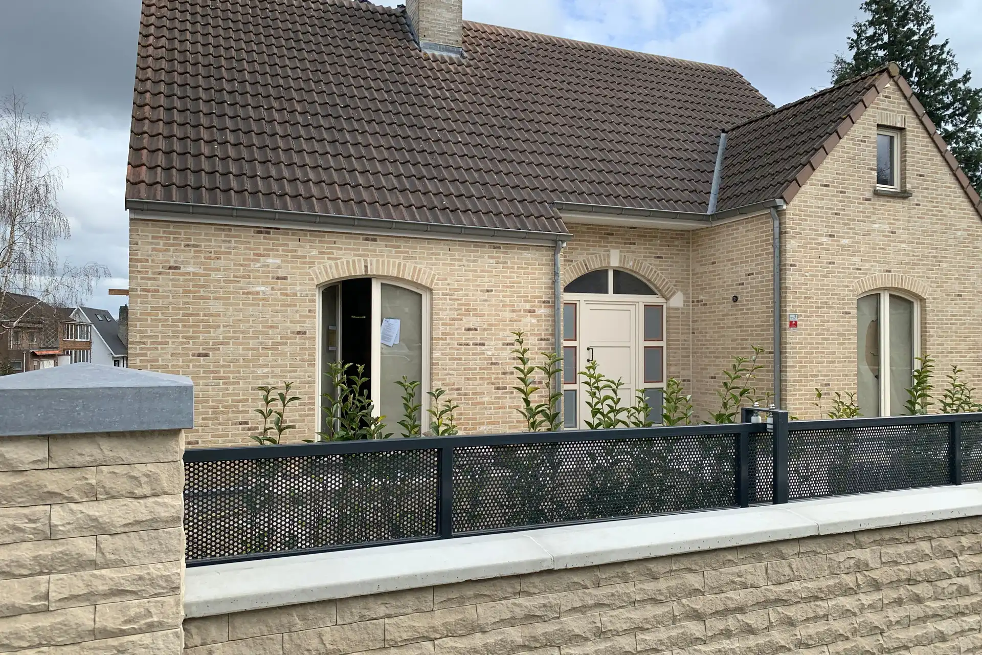 La villa avant les travaux : une seule couche habitable sous une ancienne toiture en tuiles brunes, fenêtres cintrées et porte à imposte derrière le nouveau muret de rue